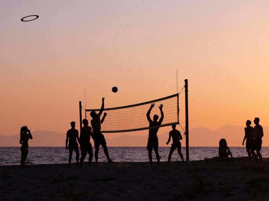 Happy group of multi-generational friends enjoying beach vacation together at sunset