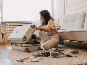 Woman cleaning hard shell suitcase with microfiber cloth after travel Placement: Top of article, before intro