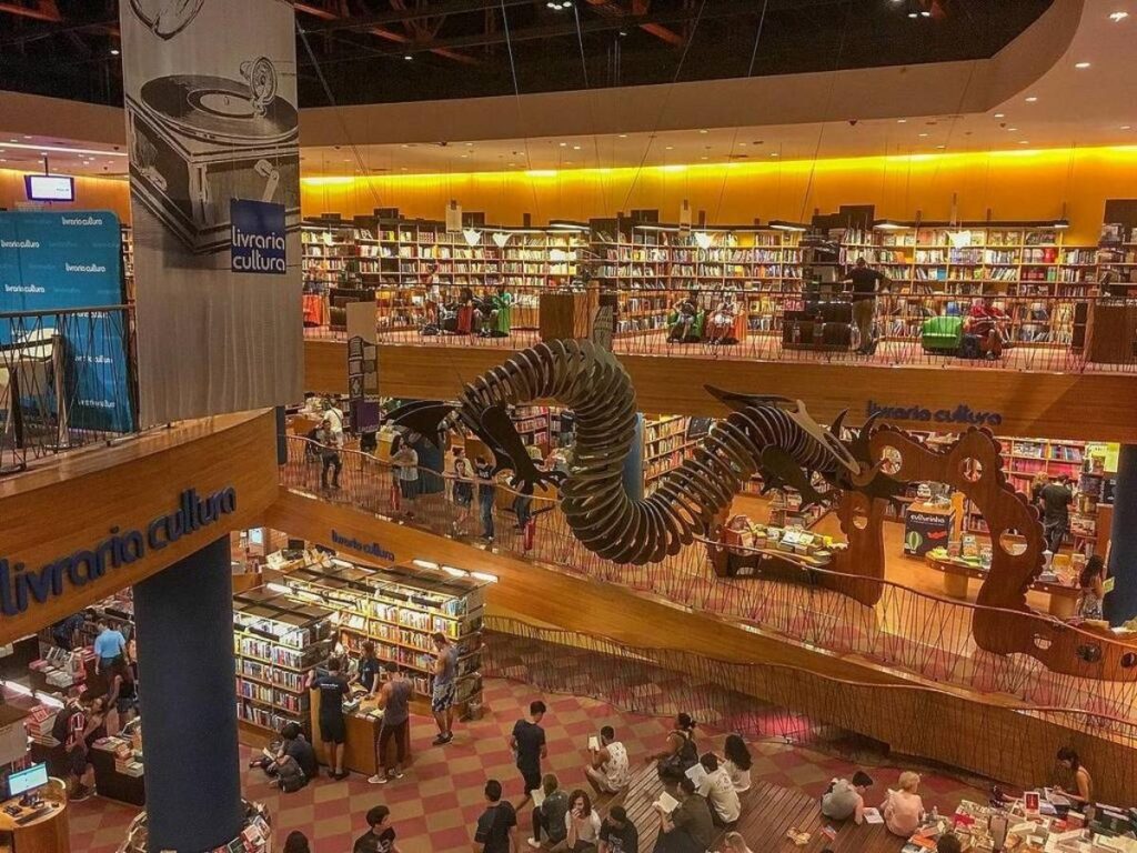 Wooden staircase auditorium with dragon sculpture hanging from ceiling at Livraria Cultura in São Paulo
