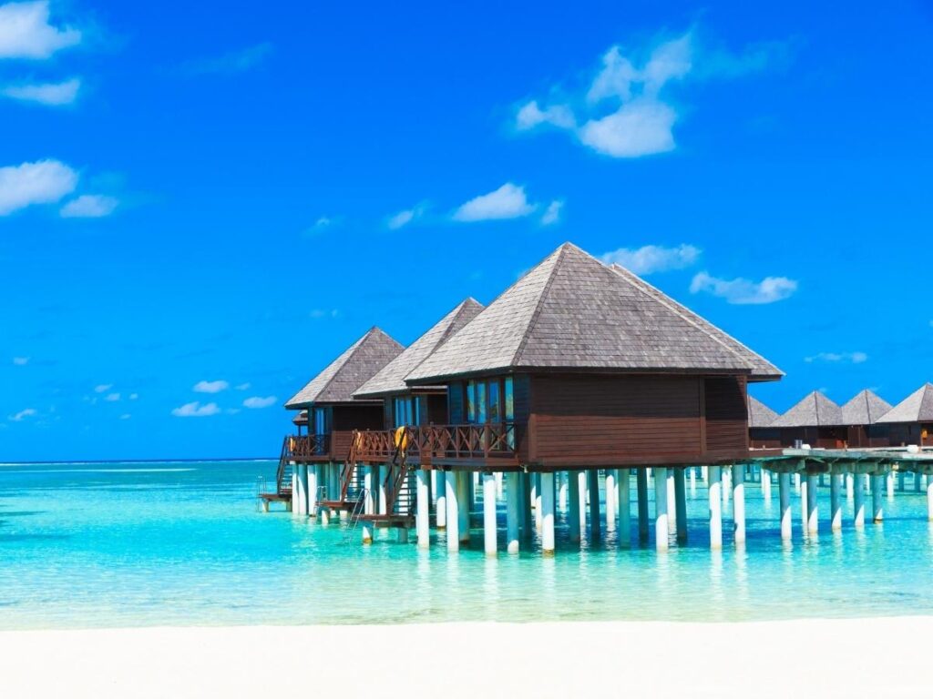 White sand beach with palm trees and clear turquoise water in the Maldives