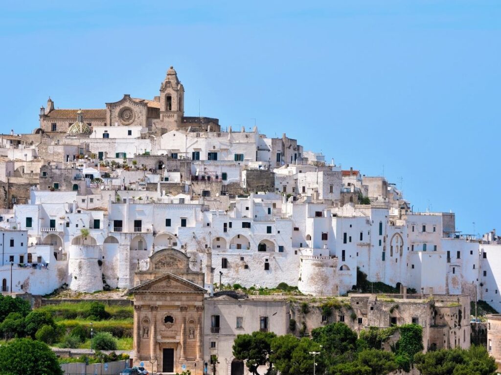 Whitewashed buildings of Ostuni gleaming in the sun with cathedral visible
