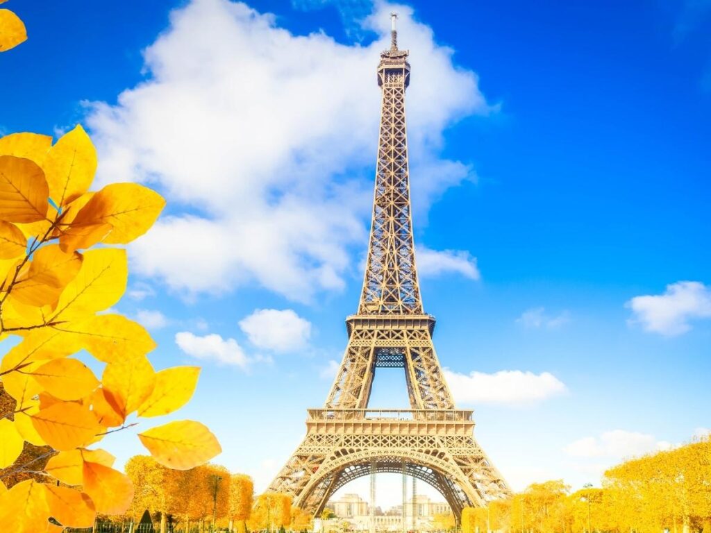 Modern coworking space in Paris with Eiffel Tower visible through large windows and remote workers at desks