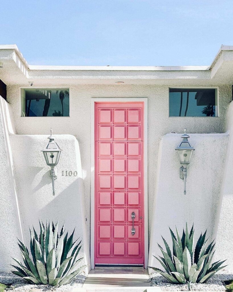 Famous pink door in Palm Springs surrounded by palm trees and desert landscaping