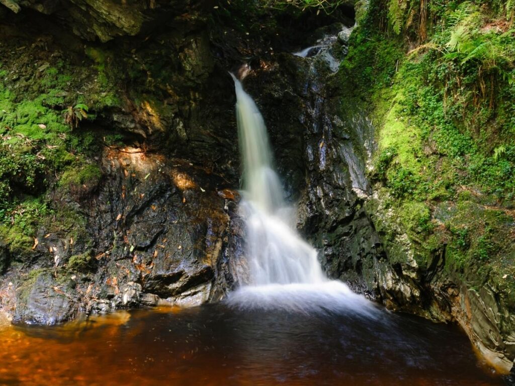 Moss covered rocks and wooden bridge in Puck's Glen near Inveraray Scotland