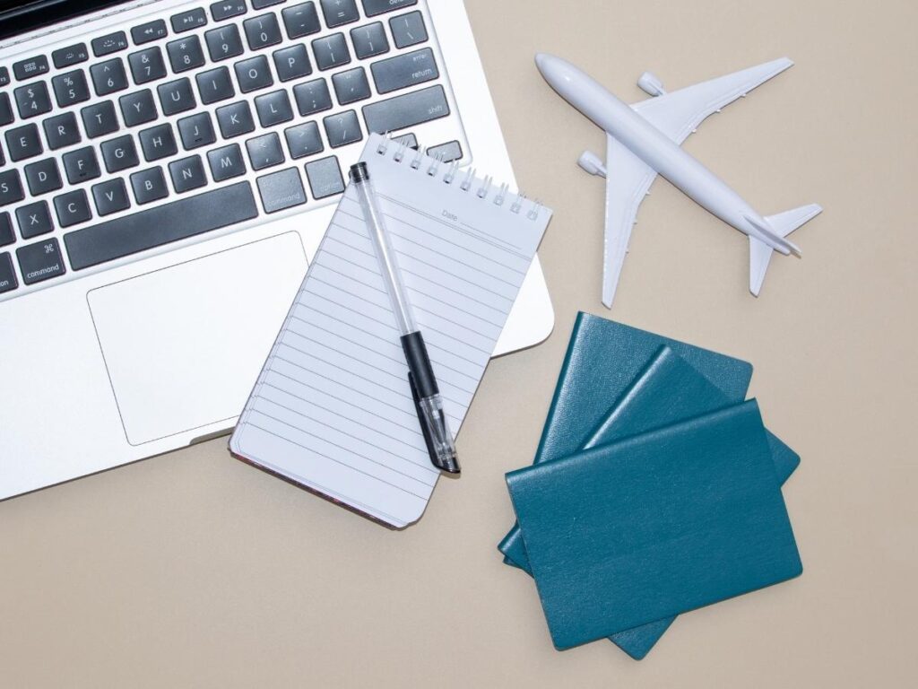 Traveler planning photo locations on laptop with camera and travel guidebook nearby