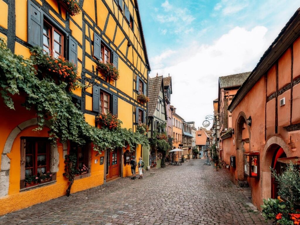Riquewihr cobblestone street with 16th century half-timbered houses in Alsace France