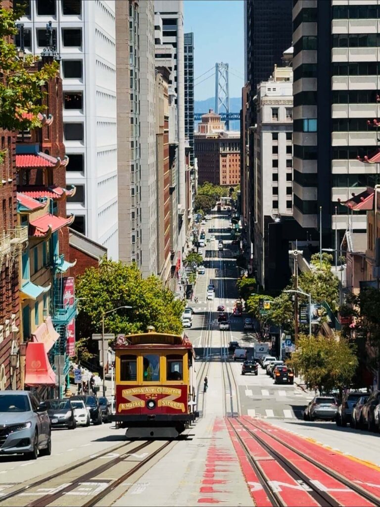 historic red cable car traveling uphill on California Street