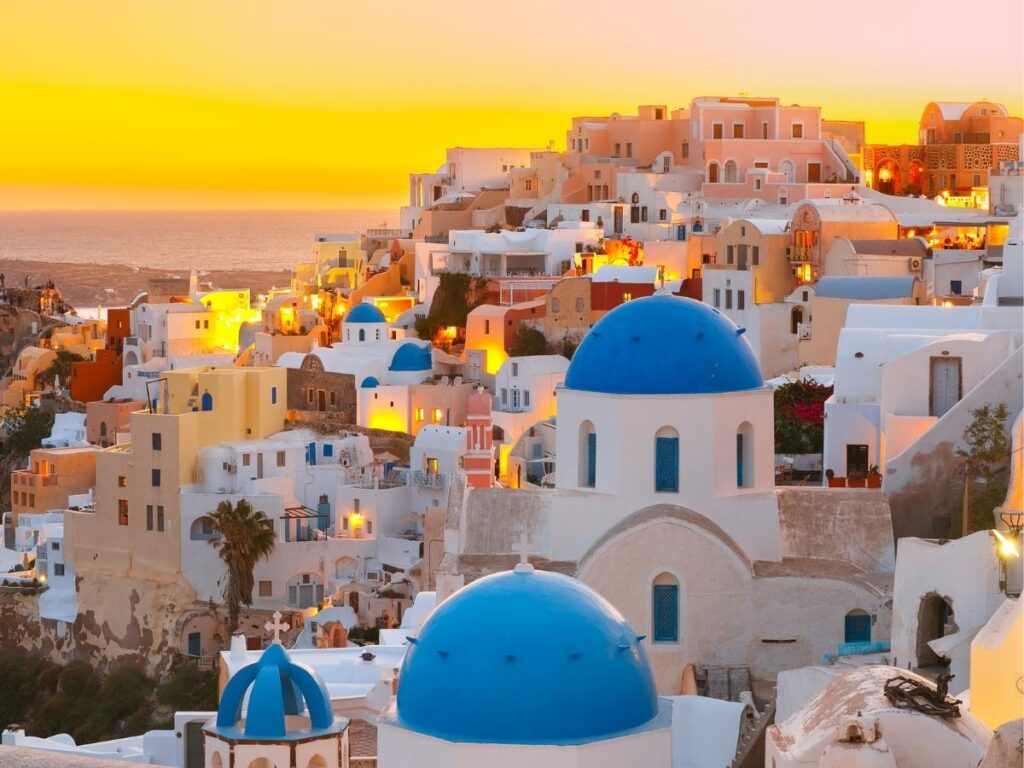 White-washed buildings and blue domes during sunset in Santorini Greece