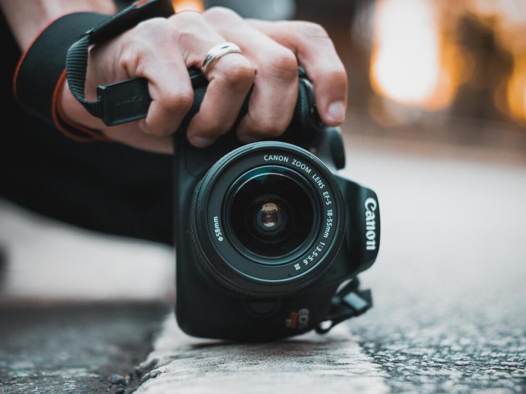 Sony mirrorless camera and Canon DSLR with lenses on wooden table with passport and map