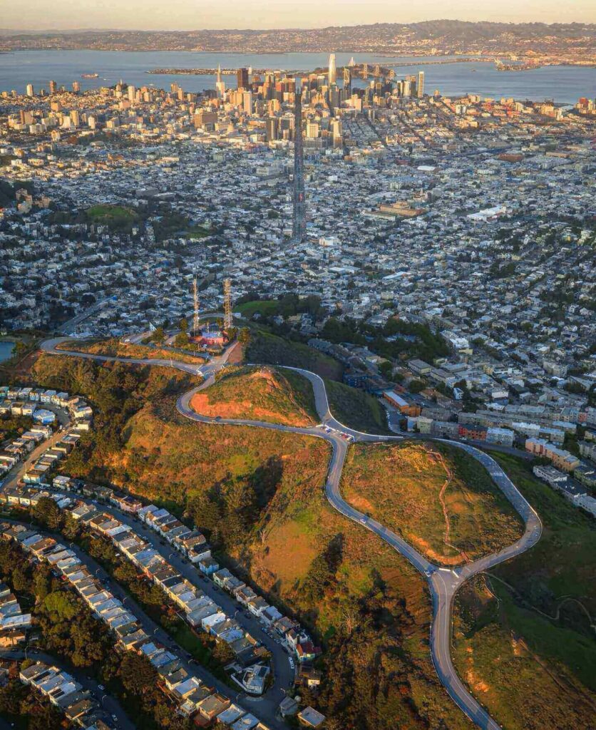 Panoramic San Francisco skyline view from Twin Peaks during sunset with city lights beginning to glow