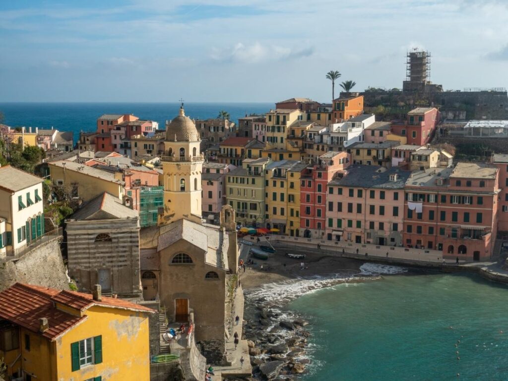 Colorful fishing boats in Vernazza harbor with pastel buildings of Cinque Terre