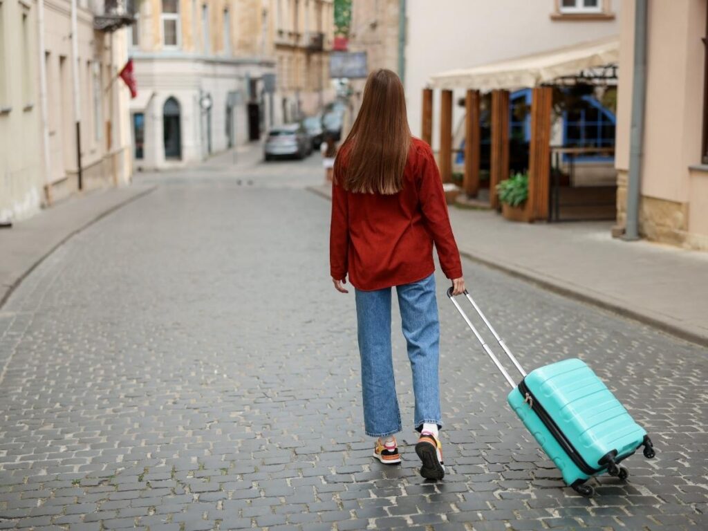 Woman with luggage looking out at a European city street, planning a long-term stay abroad