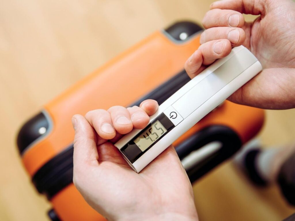 Traveler weighing luggage with a portable scale before check-in at the airport