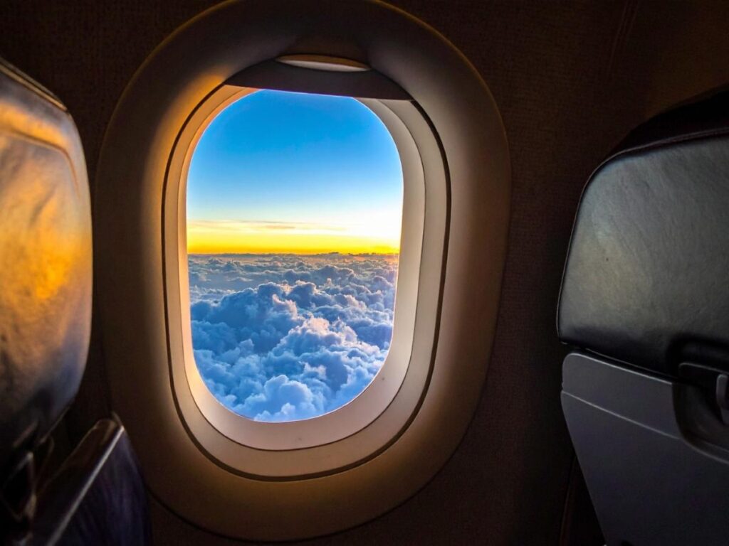 Beautiful airplane window view of clouds and sky during daytime flight