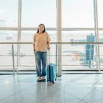 Woman wearing comfortable layered clothing at airport with luggage