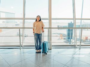 Woman wearing comfortable layered clothing at airport with luggage