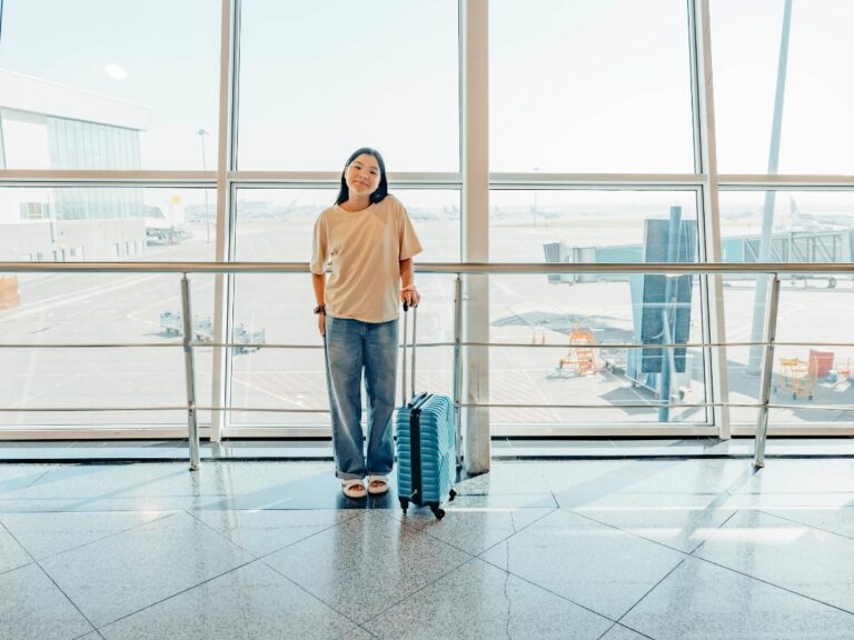 Woman wearing comfortable layered clothing at airport with luggage