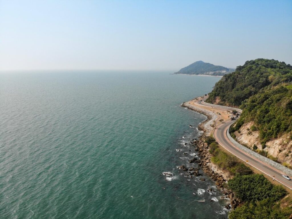 Winding coastal highway along the California cliffs with the Pacific Ocean stretching out below on a clear sunny day