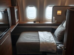 Luxury first class airline suite with flat bed and window view on a long-haul international flight