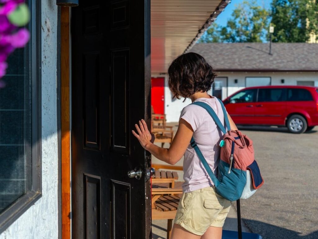 Clean affordable roadside motel exterior with car parked in front for budget road trip