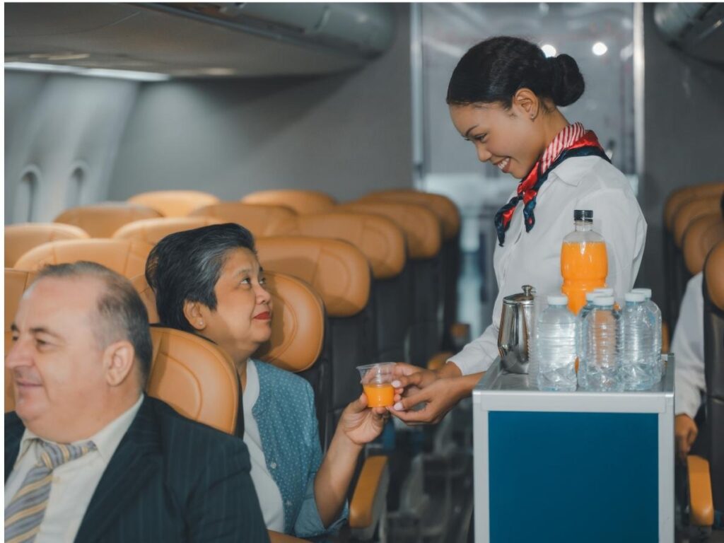 Relaxed flight attendant serving passengers during routine flight service