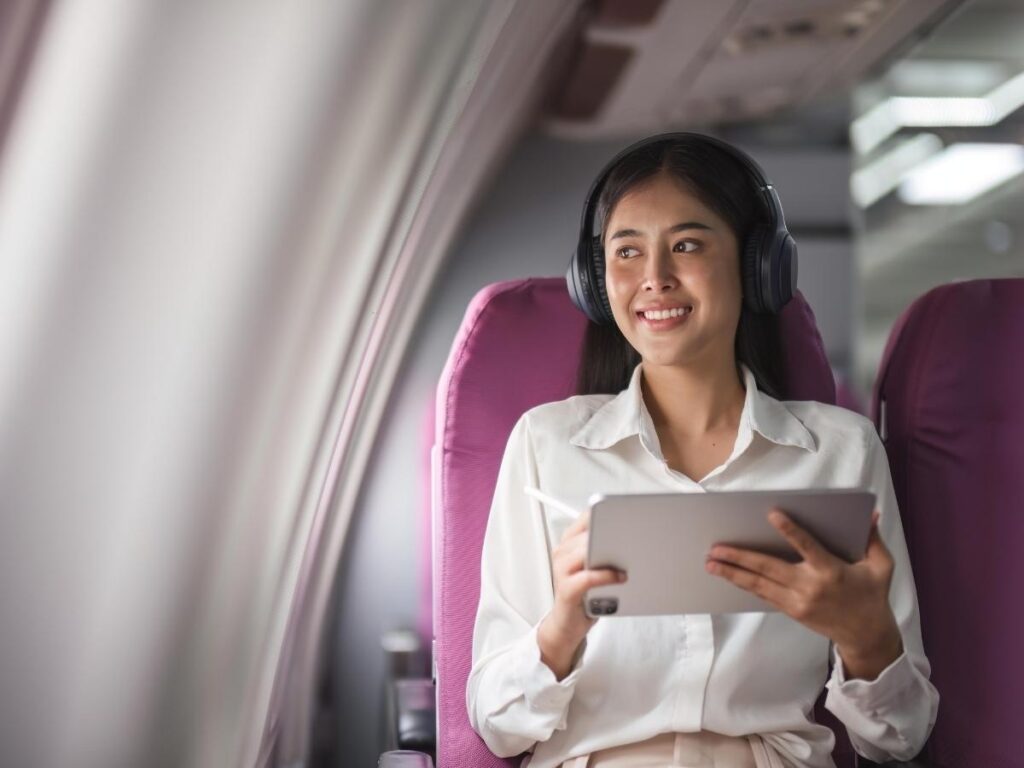 Passenger using noise-canceling headphones and watching entertainment during flight