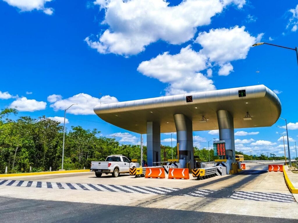 Toll booth on interstate highway showing hidden road trip costs to budget for