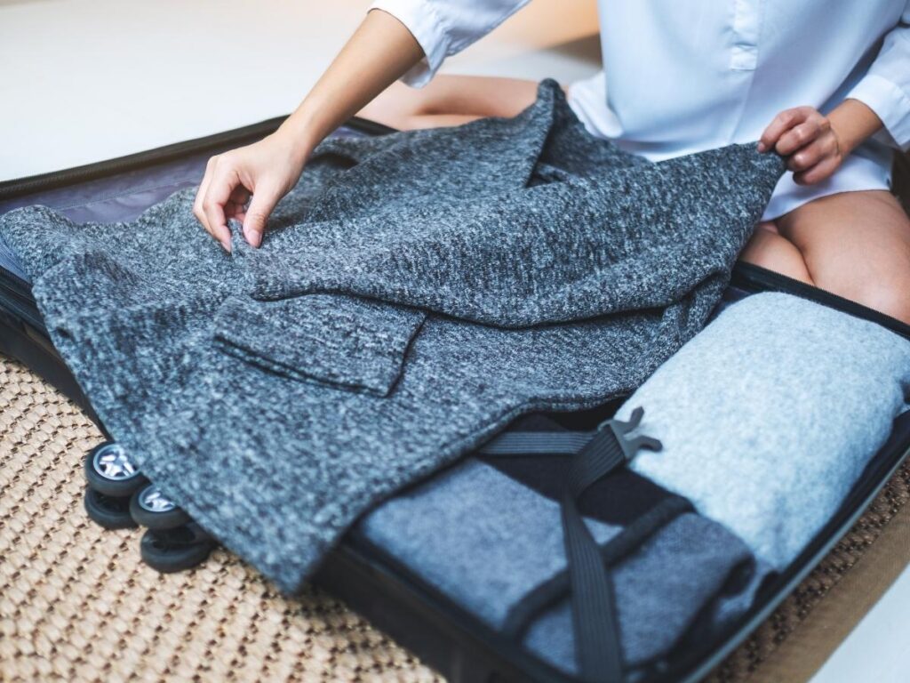 Step-by-step folding method for packing a bulky knit sweater flat into a suitcase