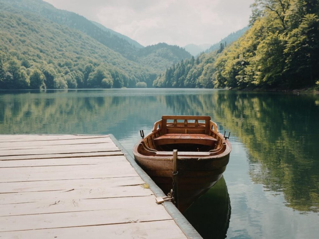 Serene Lake Atitlán in Guatemala surrounded by green volcanoes with a small wooden boat on the calm water