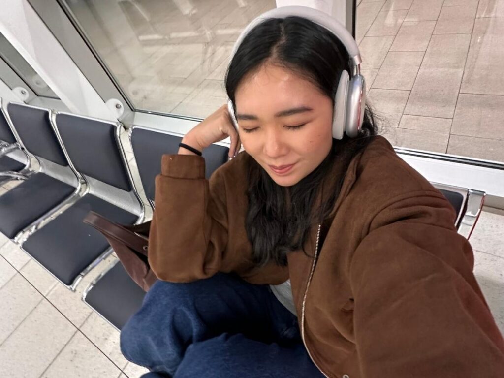 Traveler wearing noise-canceling headphones while waiting at an airport gate