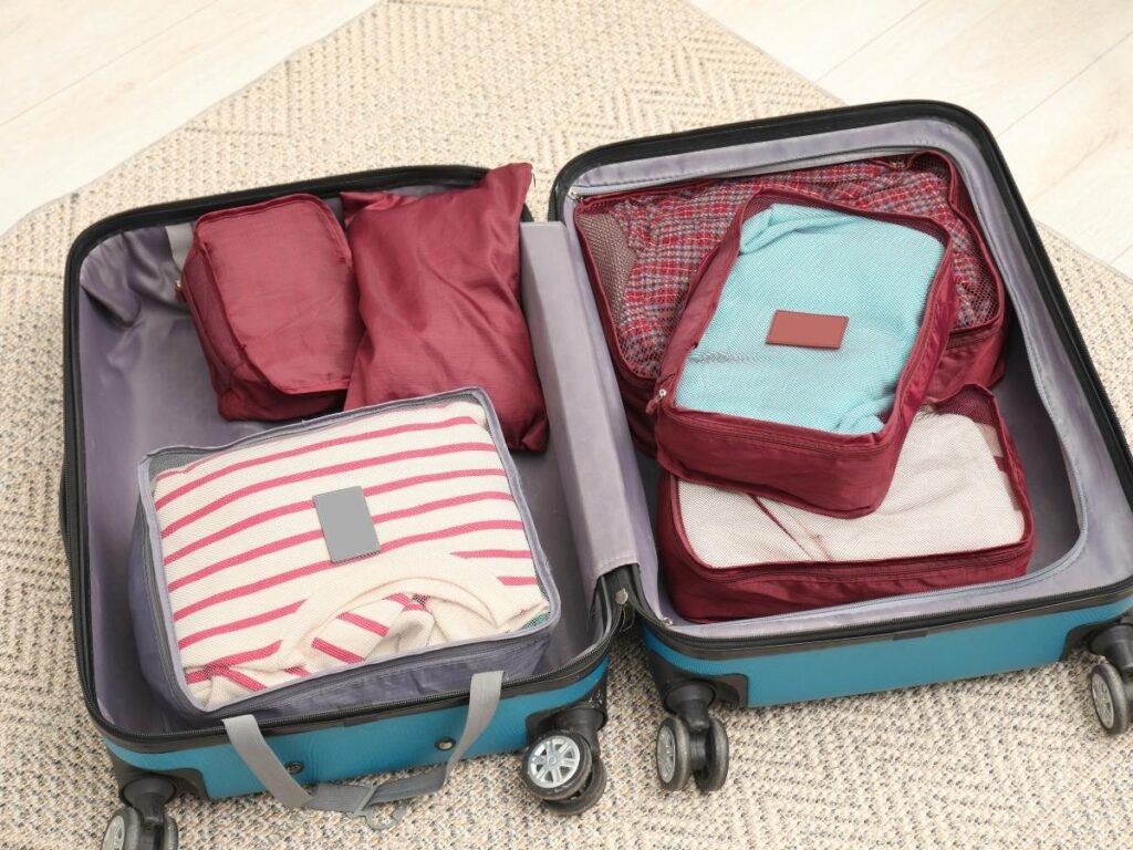 Colorful packing cubes neatly arranged inside an open suitcase on a bed