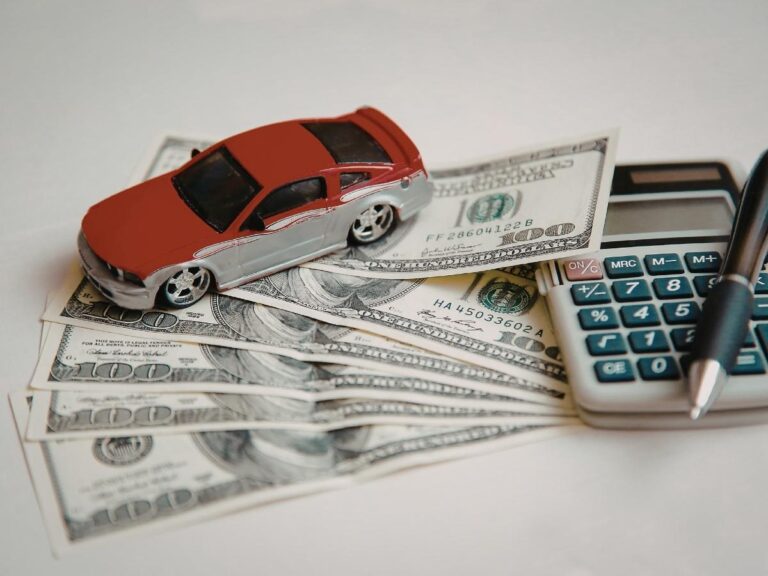 Person planning road trip budget with map and calculator next to packed car on scenic highway