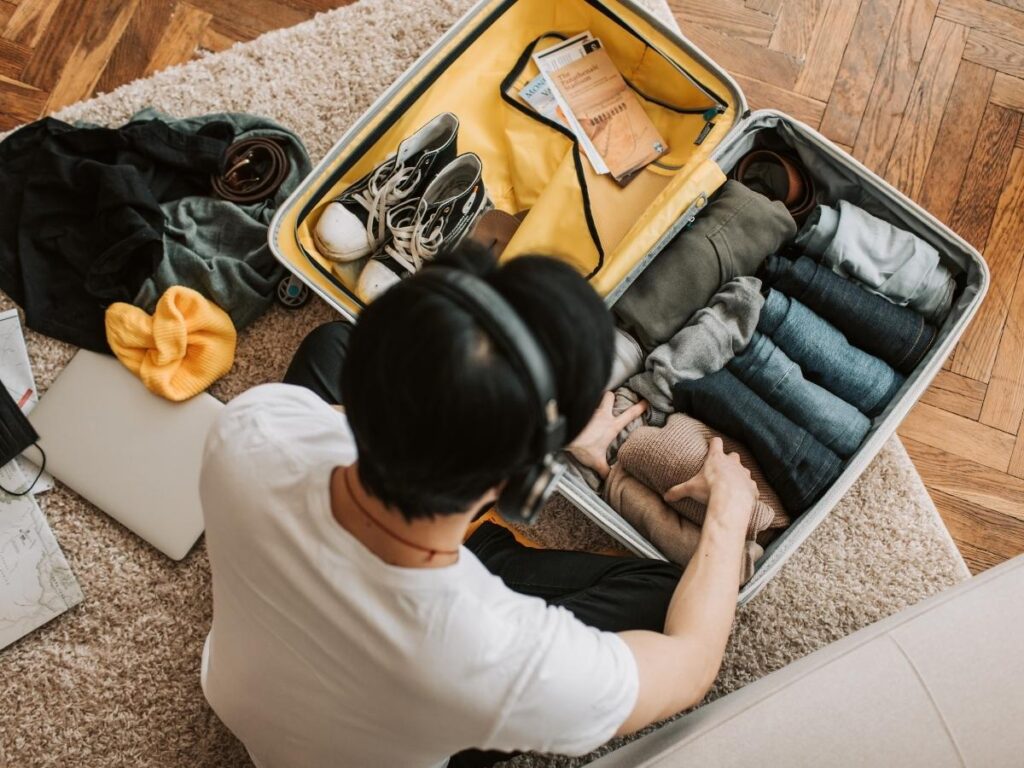 Hands demonstrating rolling clothes technique for space-saving travel packing