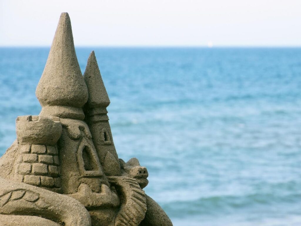 Mediterranean beach with sandcastle and warning sign in Italy