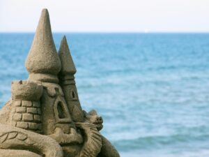Mediterranean beach with sandcastle and warning sign in Italy