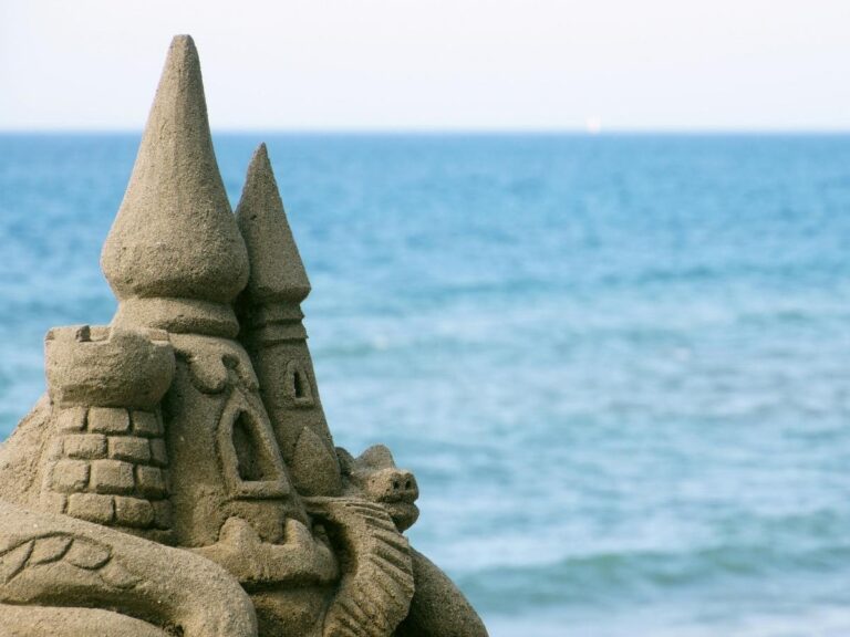 Mediterranean beach with sandcastle and warning sign in Italy
