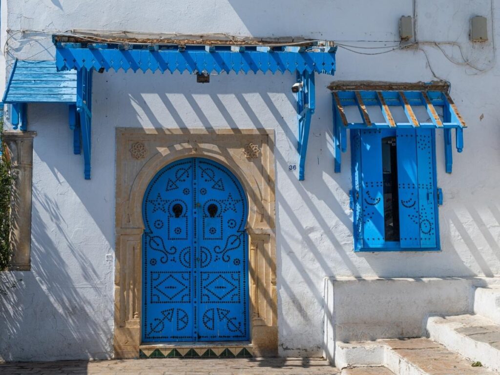 Blue painted doors and white washed walls of Sidi Bou Said Tunisia with a view of the Mediterranean Sea below