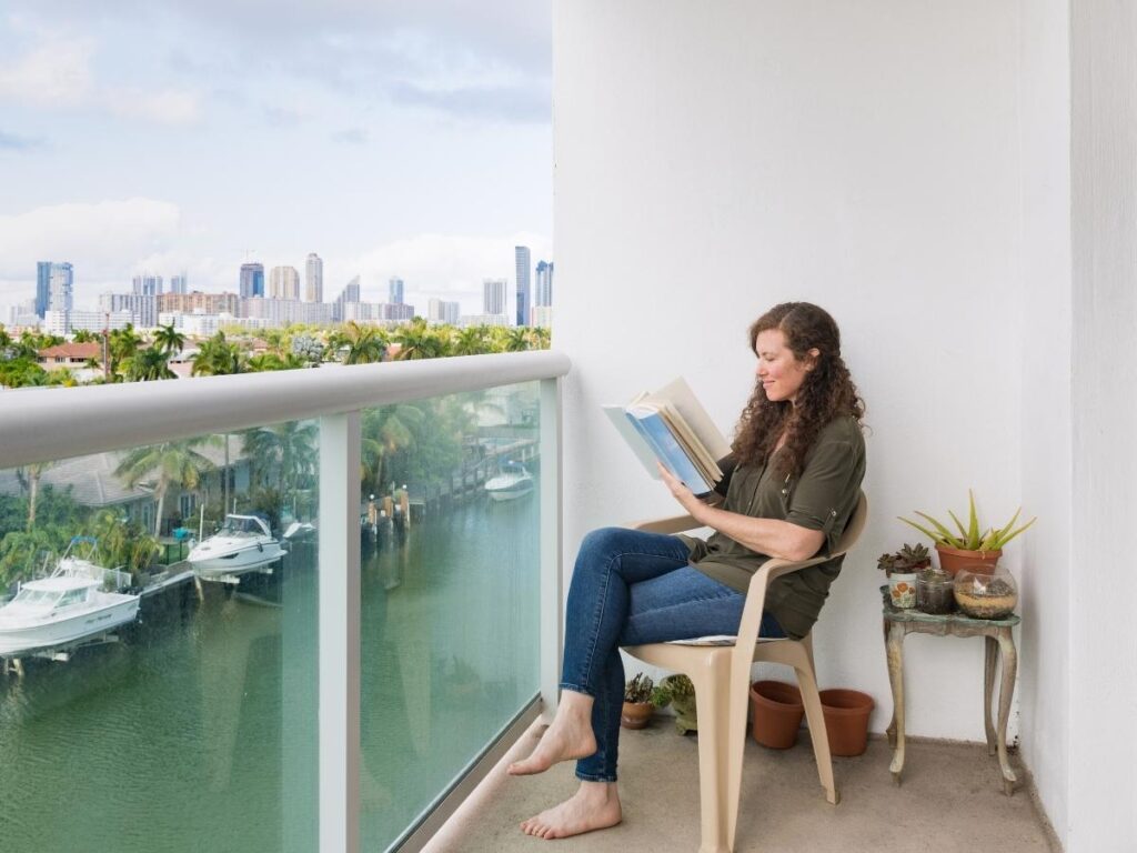 Person sitting on apartment balcony with a view of a city, journaling during a long-term stay abroad