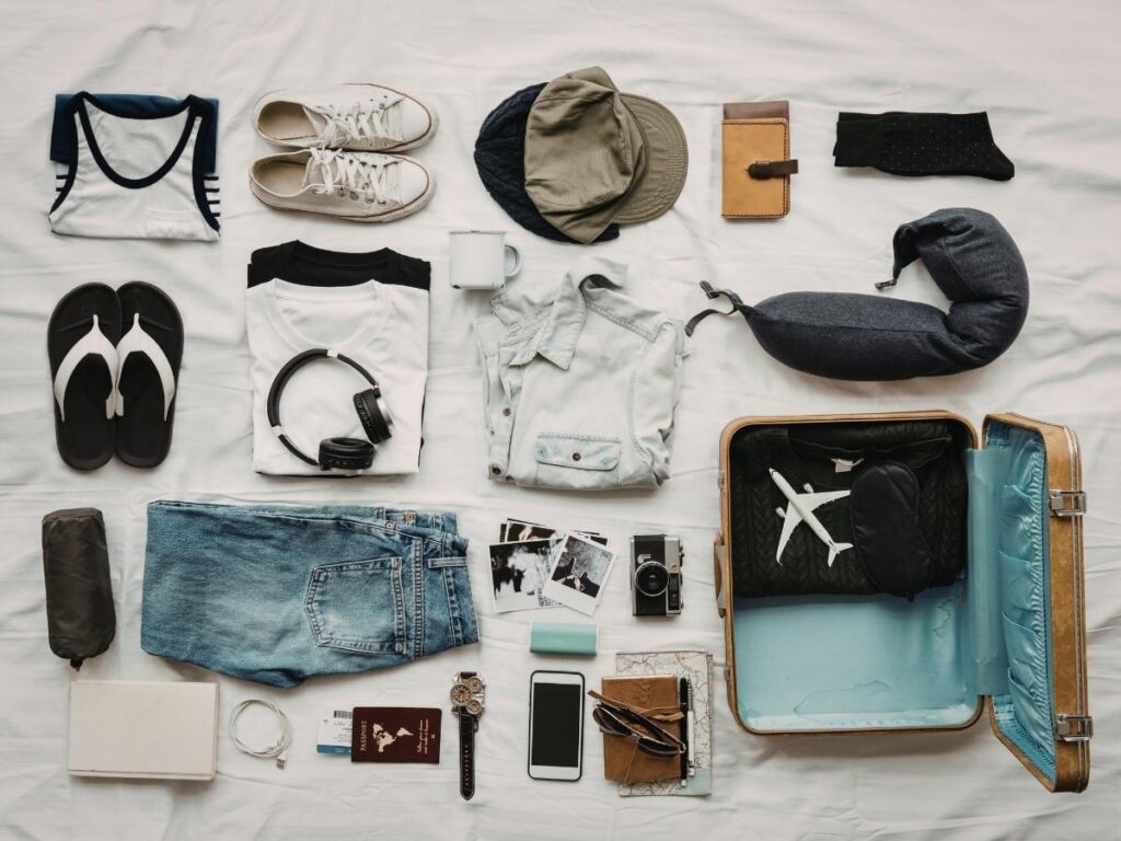 Travel outfits and clothes spread out on bed for packing selection