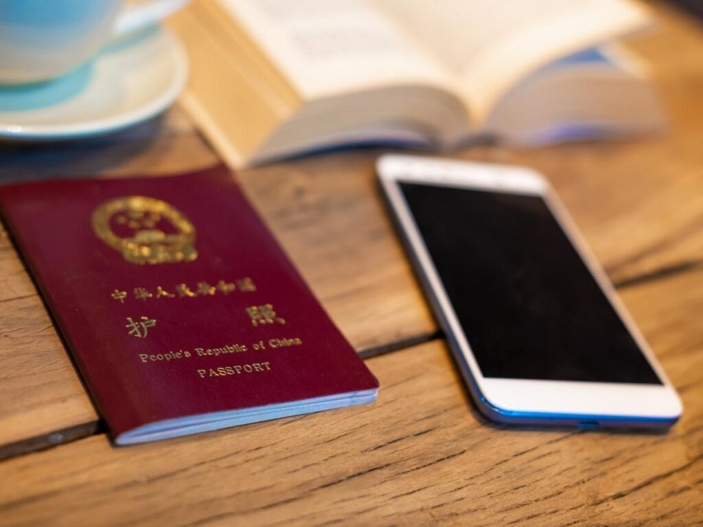Smartphone screen showing a VPN app connected and active on a wooden table beside a passport and travel documents
