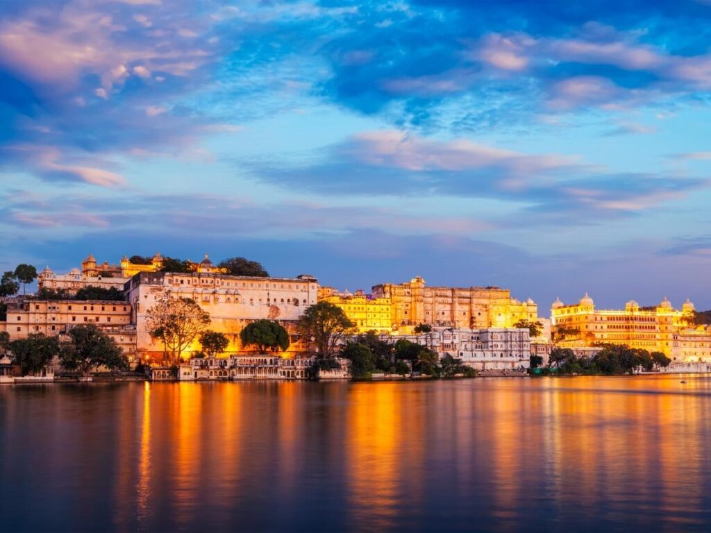 City Palace and Lake Pichola in Udaipur India glowing at golden hour with reflections on the calm water