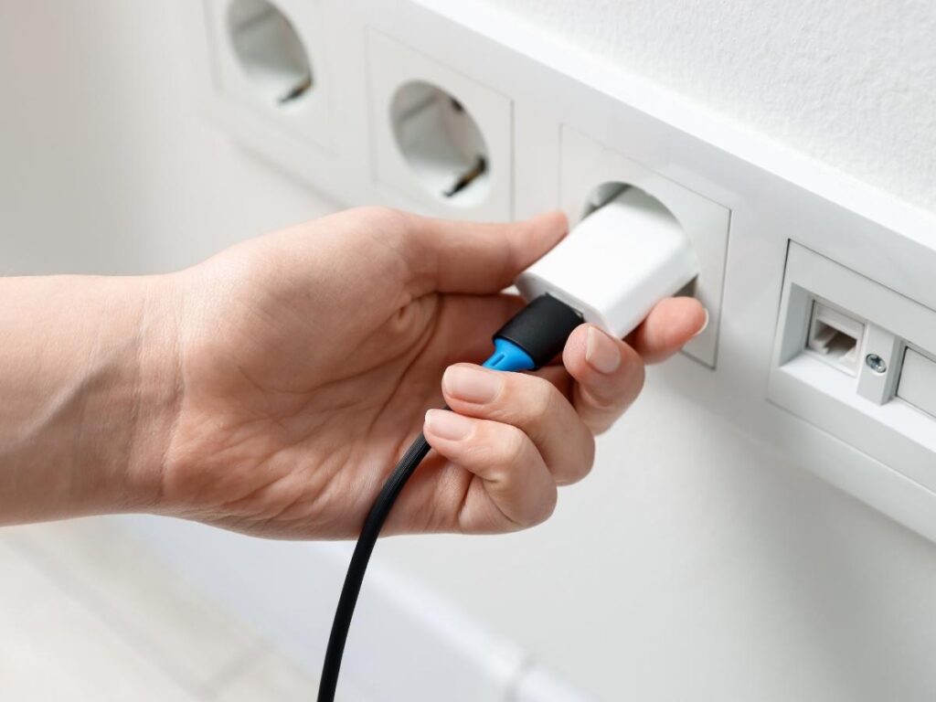 Universal travel adapter with USB ports plugged into a wall socket in a hotel room