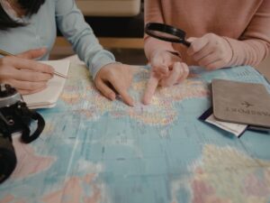 Person planning a vacation budget with a map, passport, and notebook on a wooden table