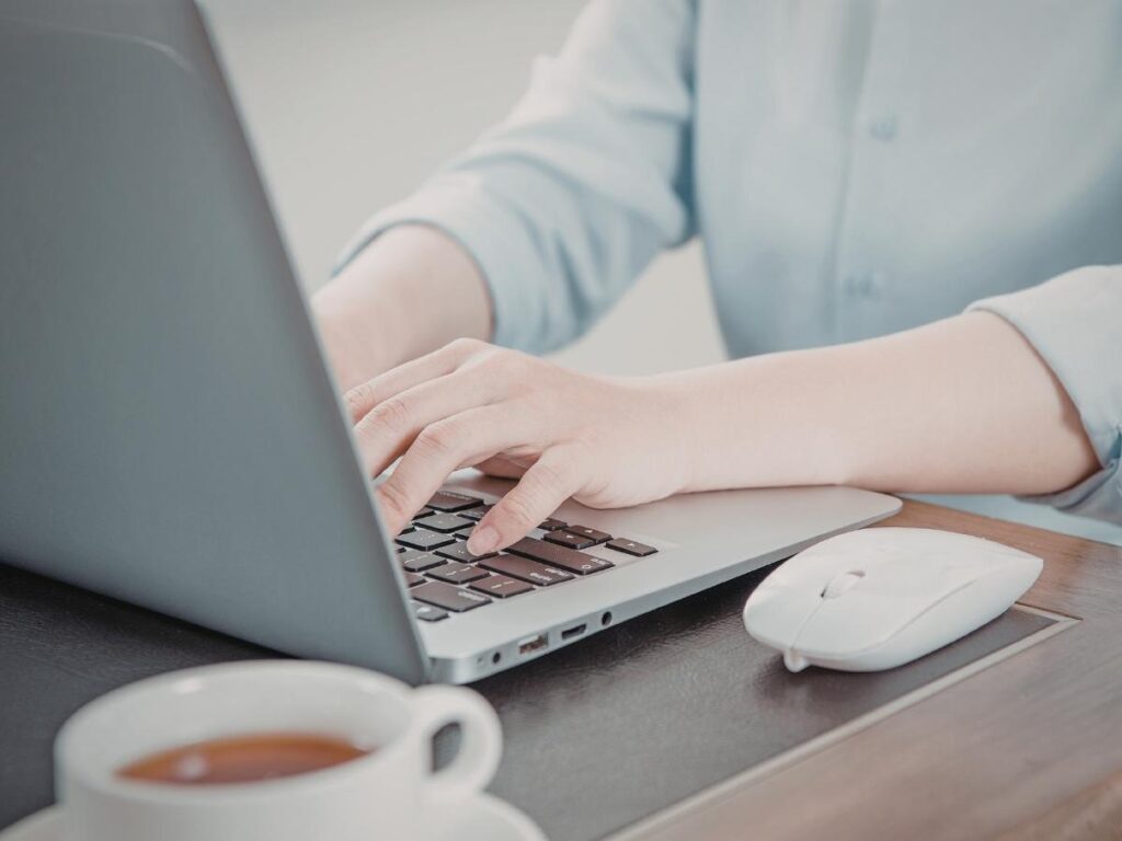 Person working on a laptop at a busy airport café with a coffee cup beside them representing public Wi-Fi security while traveling