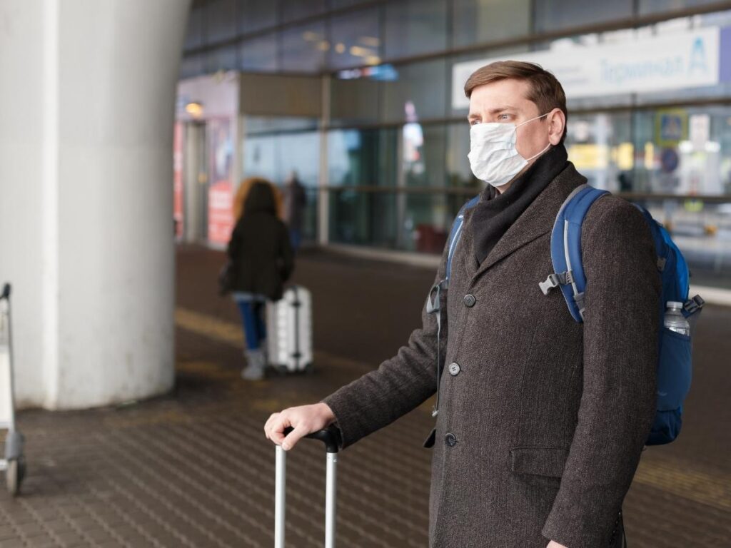 Traveler wearing layered winter clothes including coat and sweater walking through airport terminal