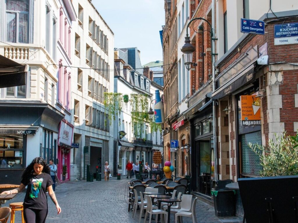 Traveler walking through a lively city neighborhood street lined with cafes restaurants and local shops
