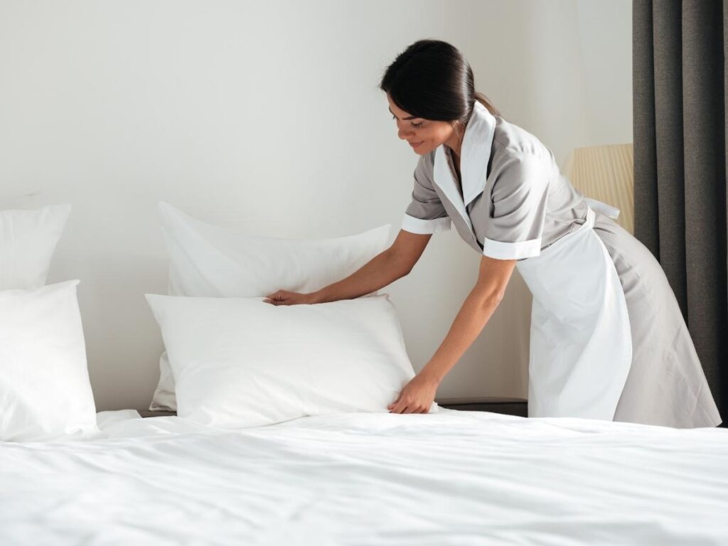 Hotel housekeeper cleaning and making up a room during a fast turnover between guests