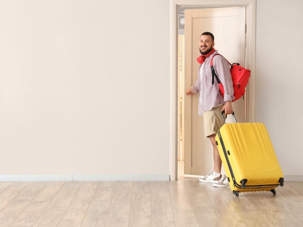 Hotel room interior with open door showing luggage trolley and hallway beyond