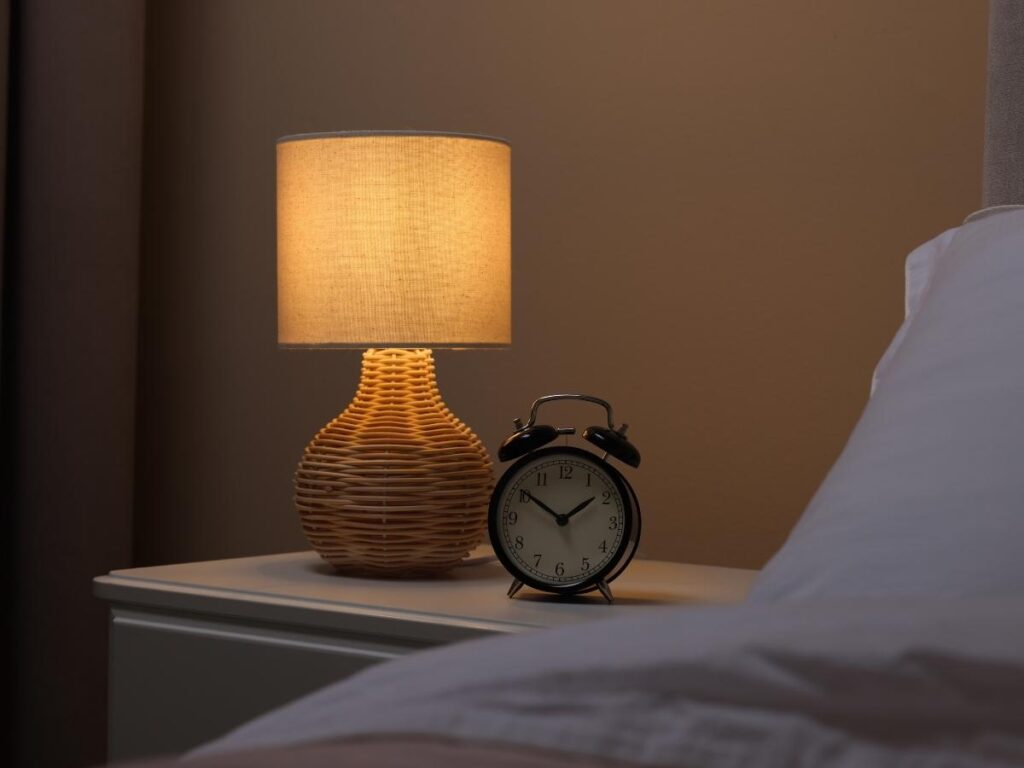 Open hotel room nightstand drawer beside lamp and clock during safety check inspection