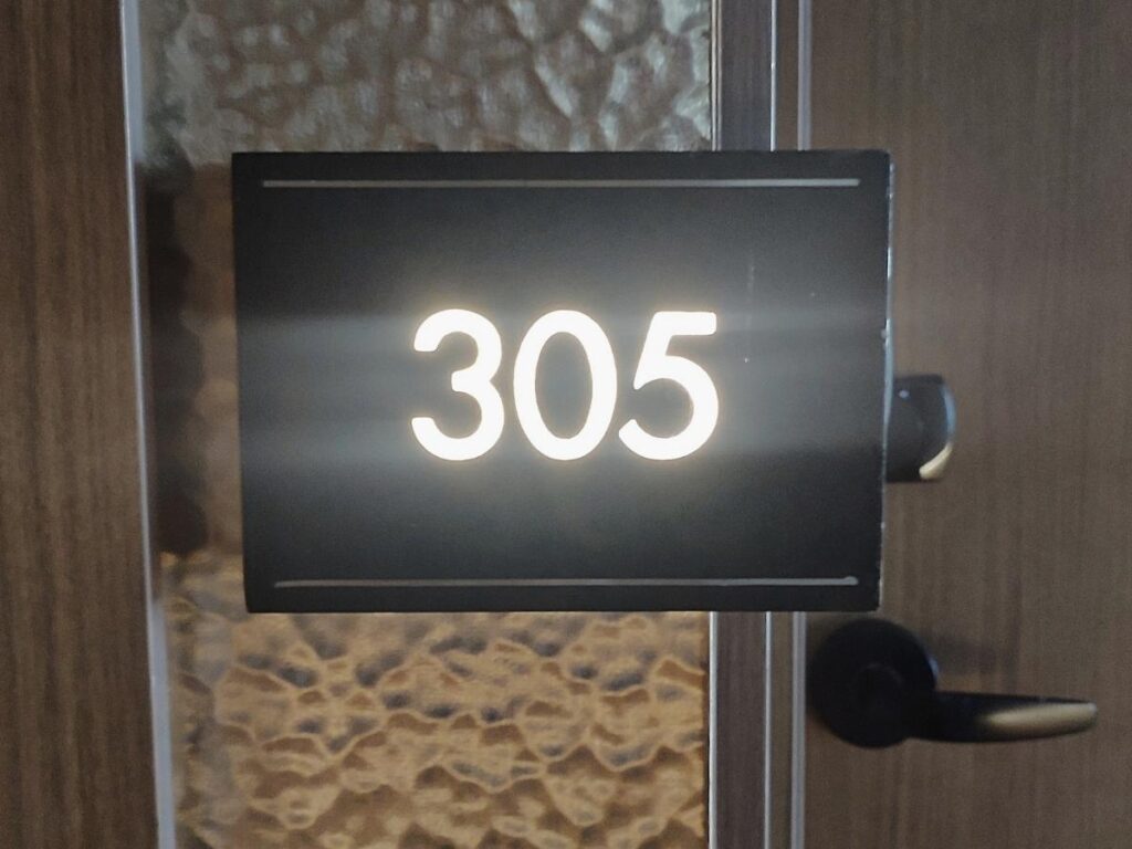 Close up of a brass hotel room number plate mounted on a wooden door in a luxury property
